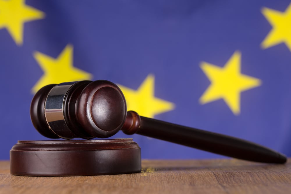 Gavel resting on sound block with european union flag in background Gavel resting on sound block with european union flag in background